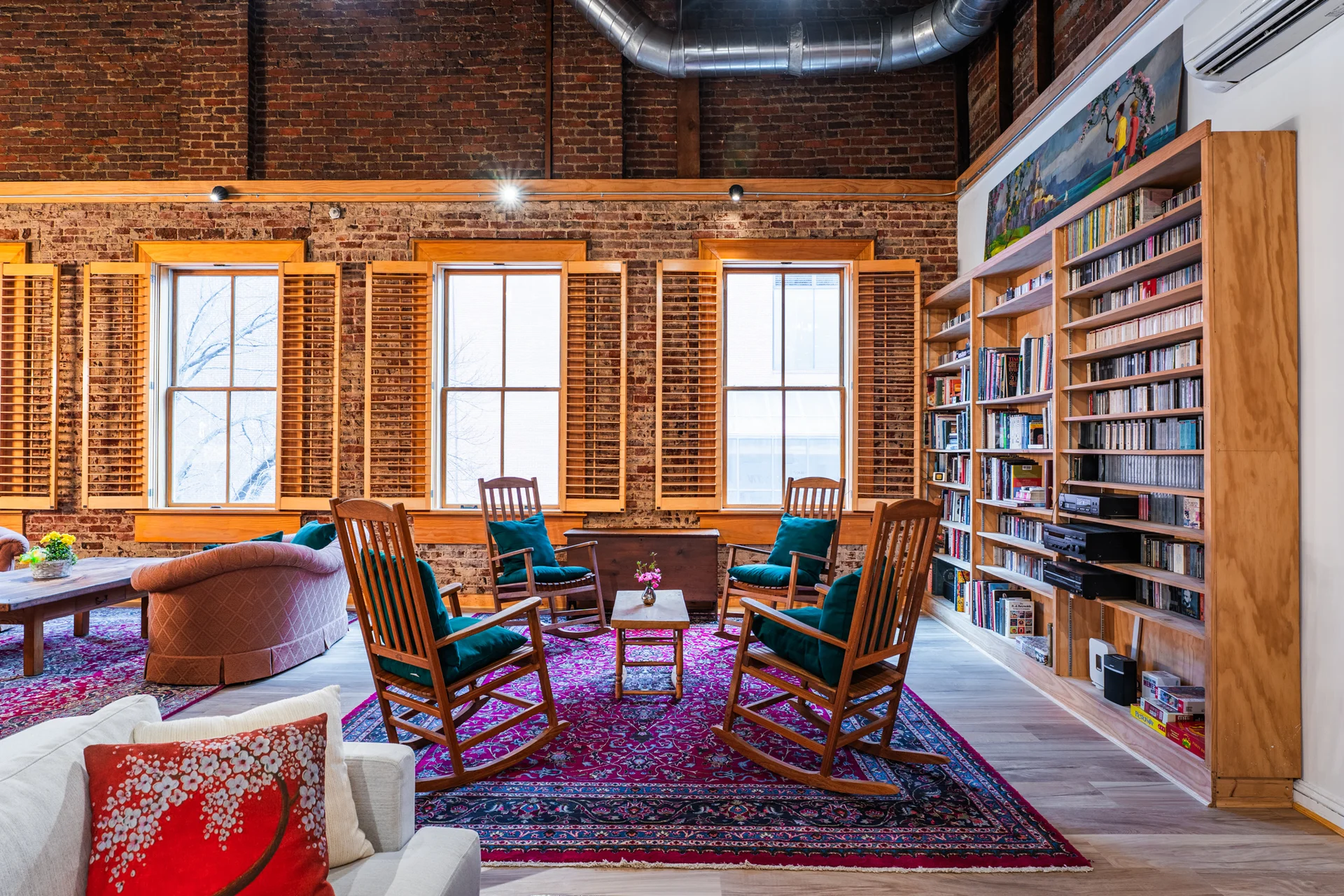Library nook with exposed brick, tall windows, and a curated bookshelf wall